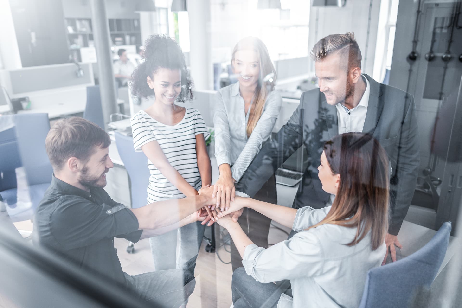 A team of professionals joining hands in a modern office, representing a professional services firm protecting client files offline